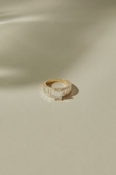 a gold ring with a baguette cut diamond set in the center on a white background