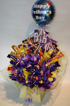 a bunch of candy in a vase with a balloon attached to the top that says happy father's day