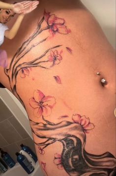 a woman's stomach with flowers on it and a tree in the back tattoo