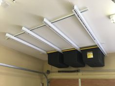 three bins are hanging from the ceiling in an empty garage with overhead lighting above them