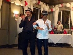 two men are dancing at a party with white and red balloons hanging from the ceiling