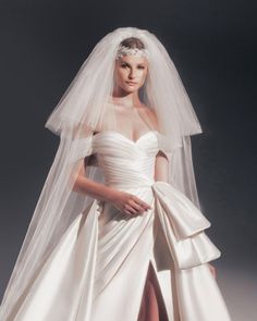 a woman in a white wedding dress with a veil on her head and skirt down