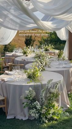 an outdoor wedding reception set up with white linens and greenery