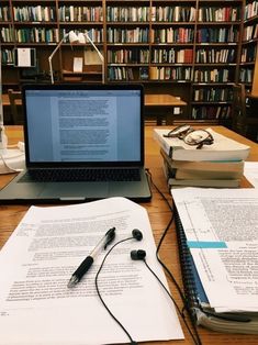 an open laptop computer sitting on top of a desk next to books and headphones