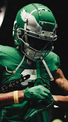 a close up of a football player wearing a green uniform and holding his hands in his pockets