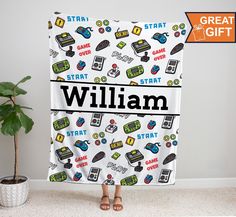 a woman holding up a personalized beach towel in front of a plant and potted plant