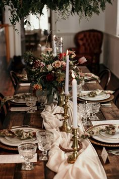 the table is set with plates, candles and napkins for an elegant dinner party