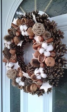 a wreath is hanging on the front door with pine cones, cotton balls and acorns