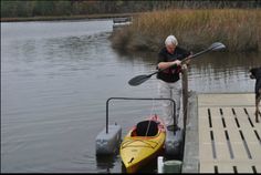 a man standing next to a yellow kayak on top of a body of water