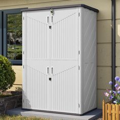 a white storage shed sitting next to a flower pot on the side of a house