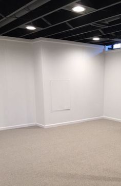 an empty room with white walls and black ceilinging is seen in this image from the corner