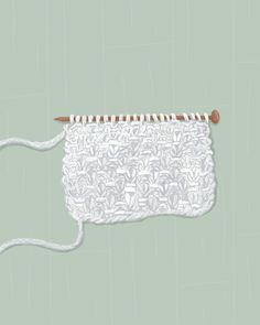 a white crocheted object with a wooden handle on a green background that appears to be knitting