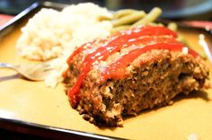 the meatloaf is covered with ketchup, green beans and mashed potatoes