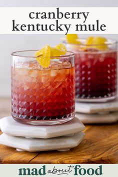 two glasses filled with drinks sitting on top of a wooden table next to each other