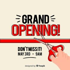 a hand holding a pair of red scissors with the words grand opening written on it