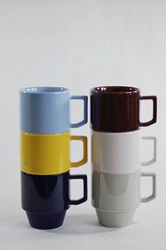 four different colored coffee mugs stacked on top of each other