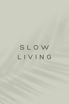 the words slow living written in black on a gray background with white and green leaves