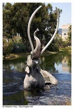 an elephant statue in the water with its trunk stretched out to it's side