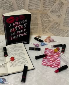 an open book sitting on top of a table next to some lipstick and other items