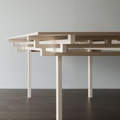 a wooden table sitting on top of a hard wood floor next to a white wall