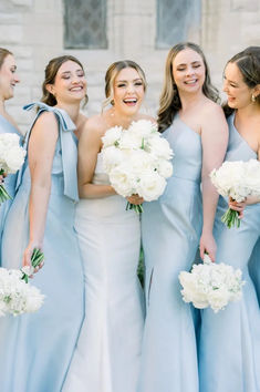 a group of women standing next to each other holding bouquets