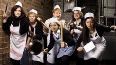 a group of women in aprons and hats posing for a photo with their cooking utensils