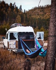 an rv parked in the woods with a hammock hanging from it's roof