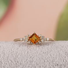 an orange and white diamond ring sitting on top of a blanket