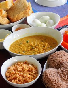 several bowls of food on a table with bread