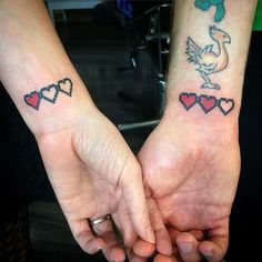 two people holding hands with matching tattoos on their wrist and arm, both have hearts in the shape of doves