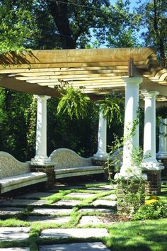 an outdoor area with stone benches and pergolated arbor in the center, surrounded by greenery