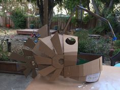 an open cardboard box sitting on top of a table in front of a tree and fence