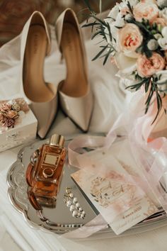 a pair of high heeled shoes sitting on top of a table next to a bouquet of flowers