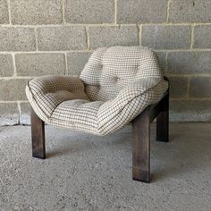 a chair sitting against a brick wall in front of a cement wall and concrete floor