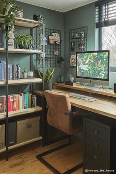 a desk with a computer and bookshelves in front of a window filled with plants