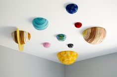 several different colored shells hanging from the ceiling in a room with white walls and flooring