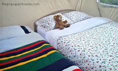 a teddy bear sitting on top of a bed next to pillows and blankets in a tent