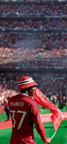 a man holding a red flag on top of a field in front of a crowd