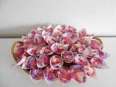 a basket filled with lots of pink flowers on top of a white table next to a wall