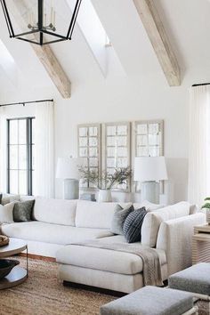 a living room filled with white furniture and lots of windows in it's ceiling