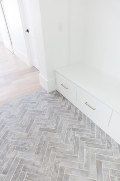 a white bench sitting on top of a wooden floor next to a wall and door