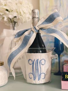 a bottle of wine in a bucket with a ribbon tied around it on a table