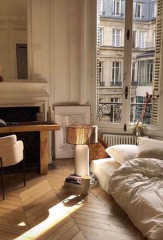 a bed sitting in a bedroom next to a desk and window with a lamp on top of it