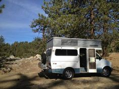 an rv parked in the woods with its door open