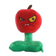 a stuffed apple sitting on top of a green object with yellow eyes and an angry face