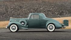 an old green car parked in a parking lot