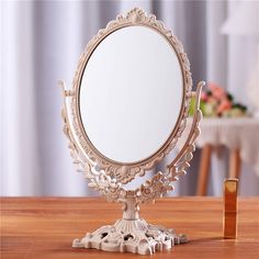 an ornately designed mirror on a wooden table with a small gold object in the foreground