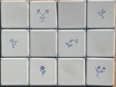 blue and white tiles with small flowers drawn on the backs of each tile, all arranged in a square pattern