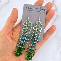 a pair of green and blue earrings in front of a card