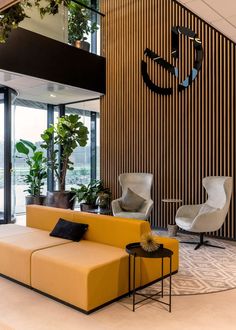 a living room filled with furniture next to a tall wooden wall and planters on either side of the couch